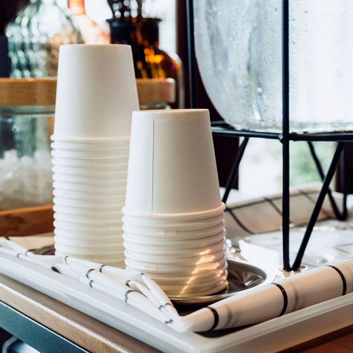 White paper coffee cups sit stacked on table